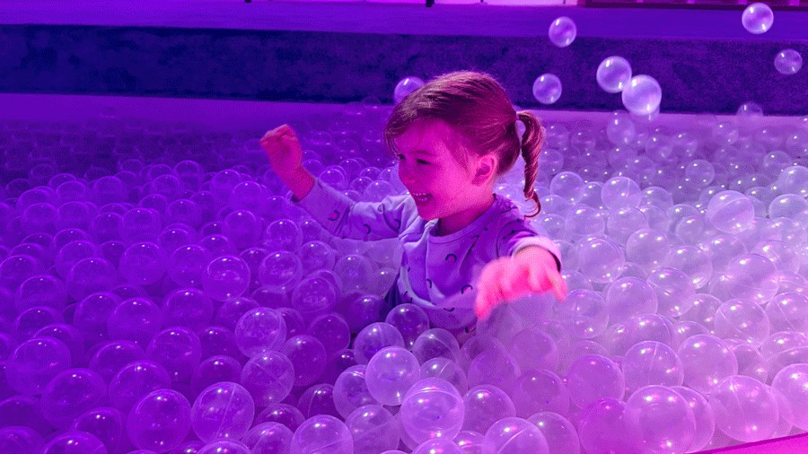 young girl throwing bubble balls in the ball pit at Bubble Planet