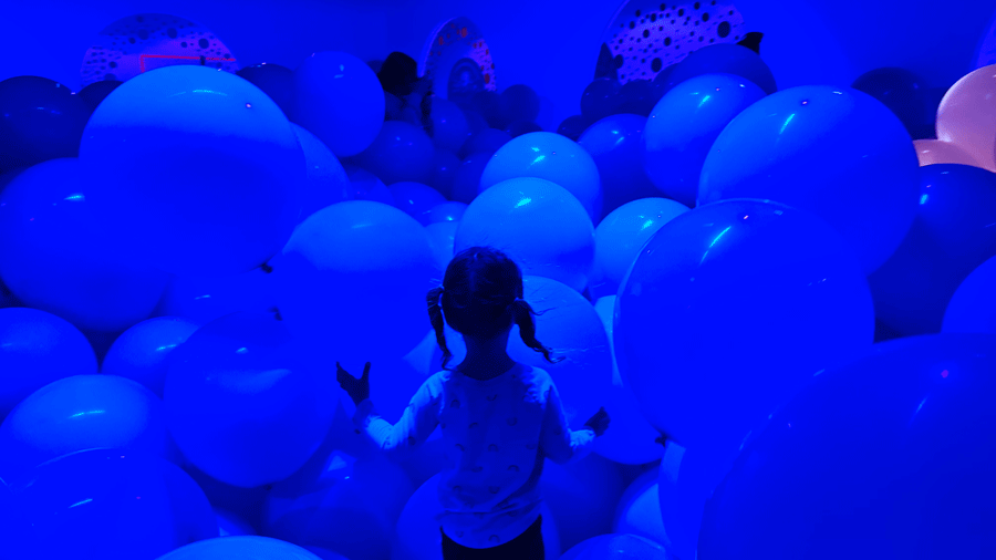 young girl stepping into ocean room with latex balloons at Bubble Planet in Bellevue