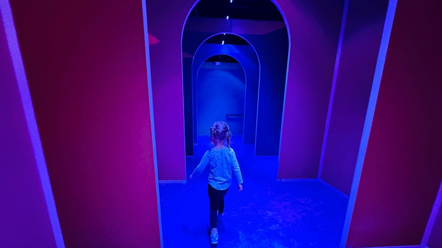 young girl walking down a rainbow hallway at Bubble Planet, an immersive experience for families