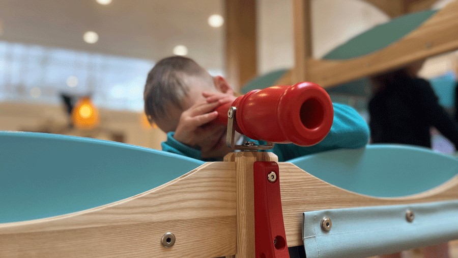 young boy with a telescope engaging in imaginary play at the Holiday Cafe, a Montessori and Waldorf based play space