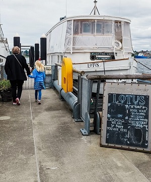 An adult and child walk on a dock approaching the houseboat MV Lotus for afternoon tea