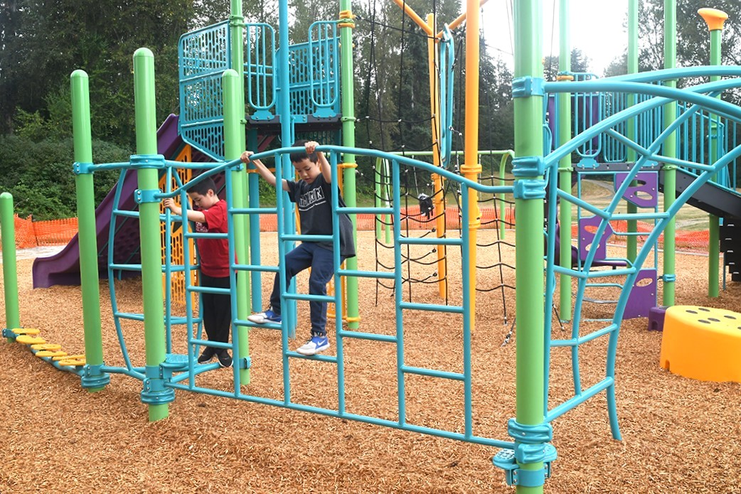 Boys balance and play on playground equipment newly installed at Renton's Cascade Park. Colorful equipment and a wide purple slide are key features at this fun new playground at a quiet neighborhood park