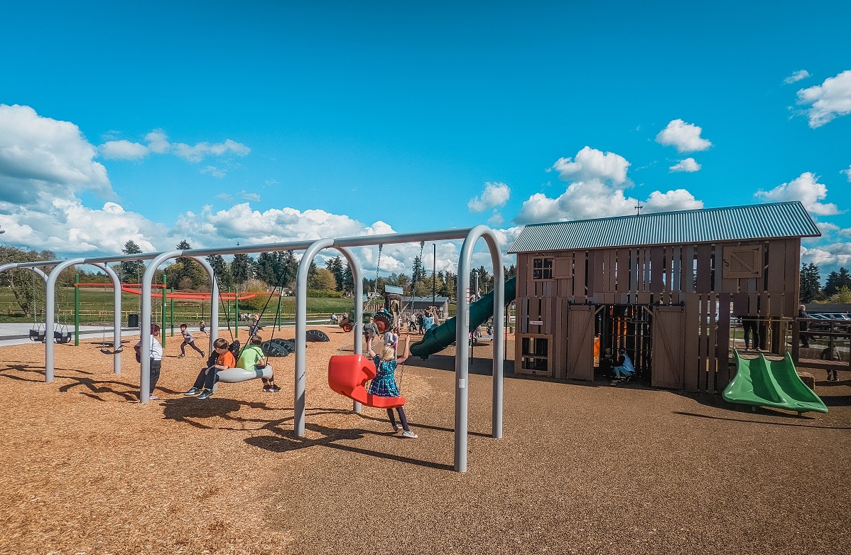 Kids play on a really good bank of swings found at the new Edgewood Community Park playground in Pierce County, outside of Seattle