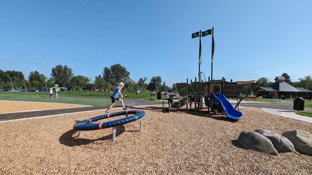 A girl walks on a tilted spinner balance element at the new playground at Van Doren’s Landing Park in Kent