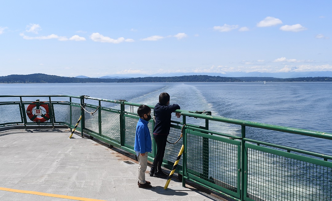 boys looking back at bainbridge island on return ferry trip to seattle