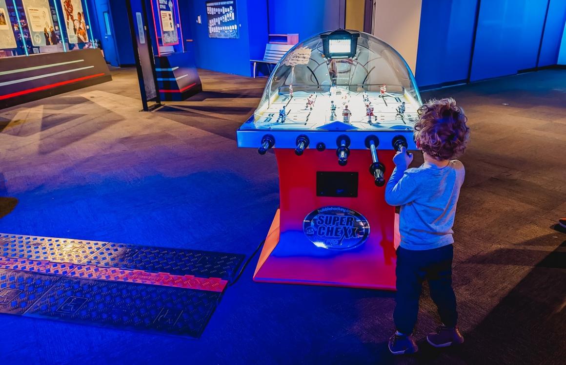 Playing bubble hockey kind of like foosball hands-on game at Hockey: Faster Than Ever exhibit at Pacific Science Center