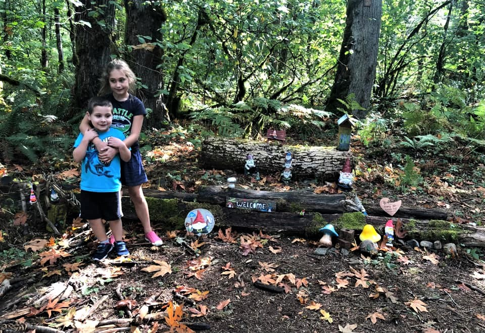 Happy siblings posing by a log along Maple Valley's gnome trail fun for seattle-area kids and families