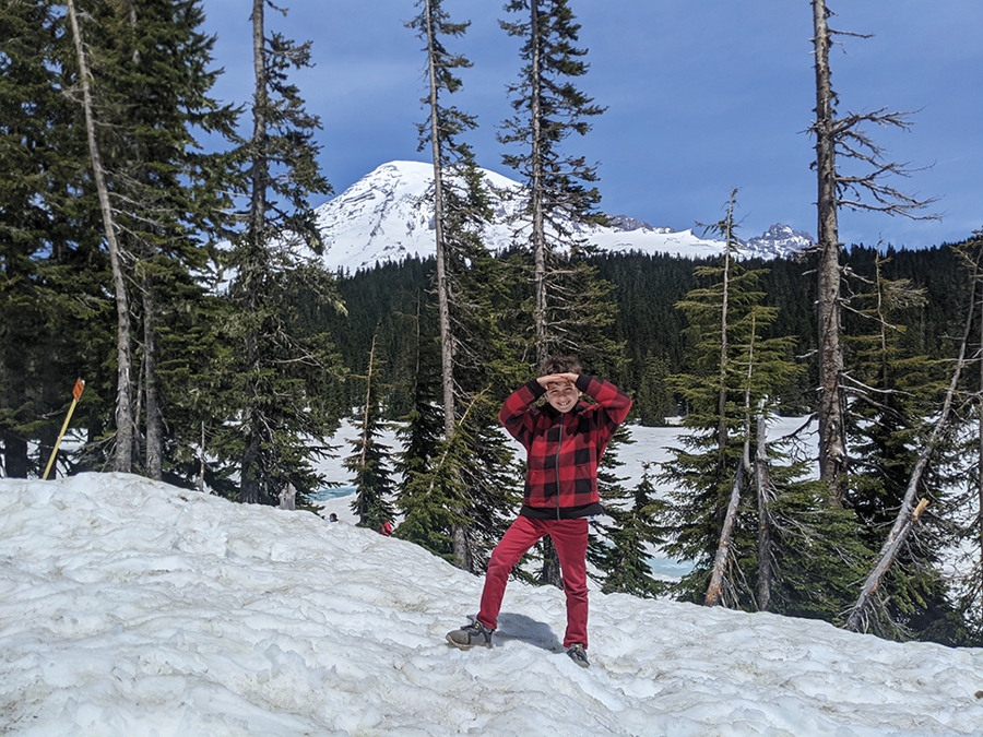 child standing in the snow with Mt. Rainier in background