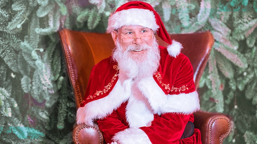 Santa sits in a snowglobe for pictures with kids