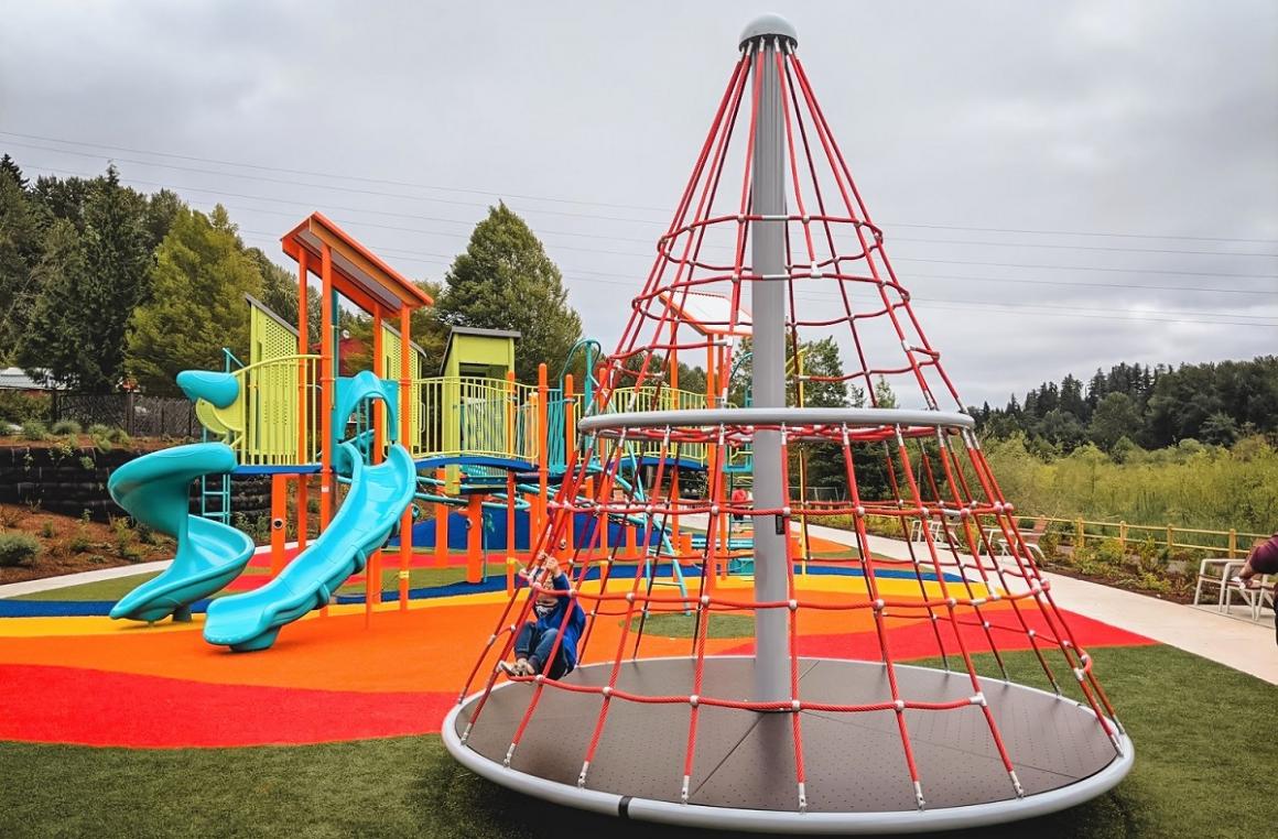 Cone climber cargo net merry go round at colorful new Totem Lake playground