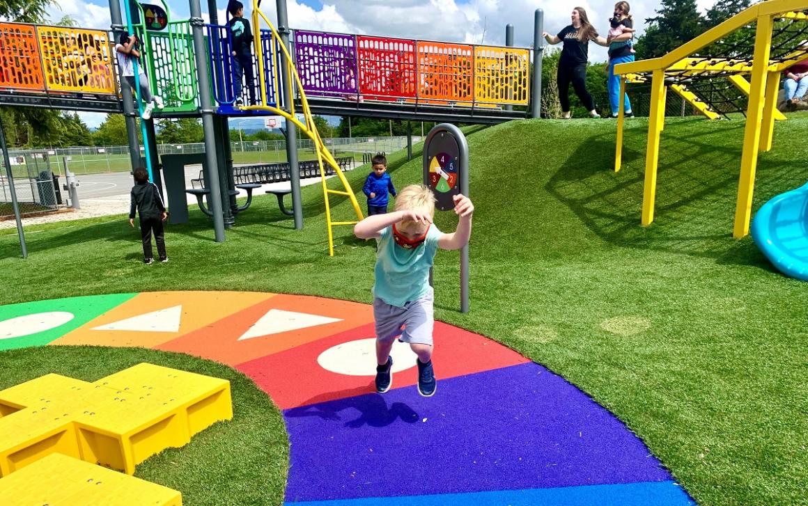 Boy running along rainbow game path at West Fenwick Park playground in Kent near Seattle new playground fun for kids