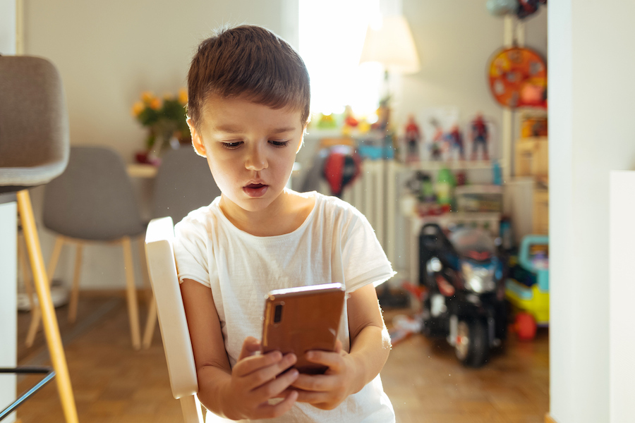 young boy looks at a cell phone with a concerned expression