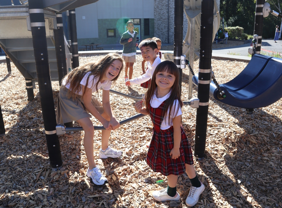 Kids of various ages playing outside together at a k-8 school