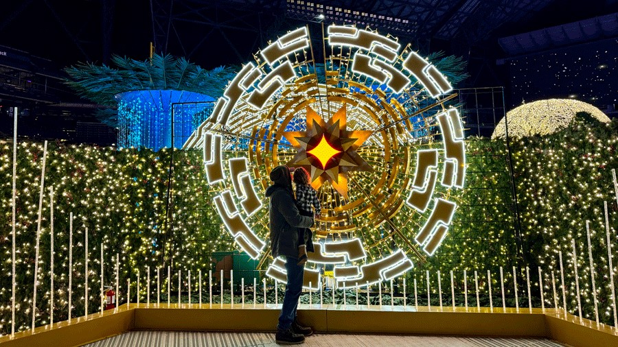 father and daughter looking at huge light sculpture at the Enchant Christmas maze, a holiday attraction for families