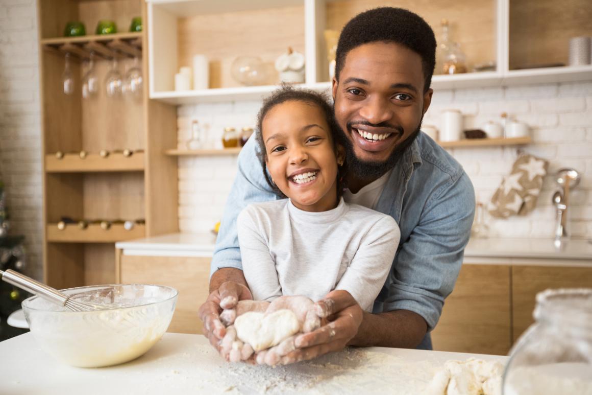 dad holding his daughter's hands with heart shaped pastry baking together