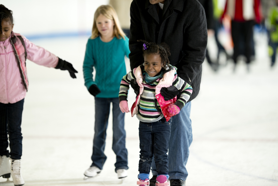 Girl and adult at an indoor ice skating rink near Seattle holiday family fun