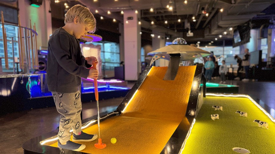 Young kid playing indoor mini golf at Bellevue Par1 Mini Golf, a Seattle-area indoor activity for families