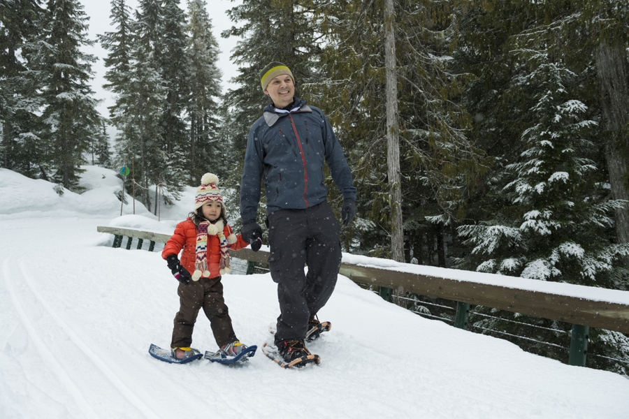 Dad and child walking in snowshoes having a winter family adventure