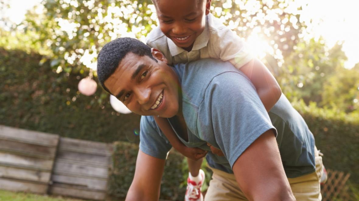 Little boy riding on dad's back outside