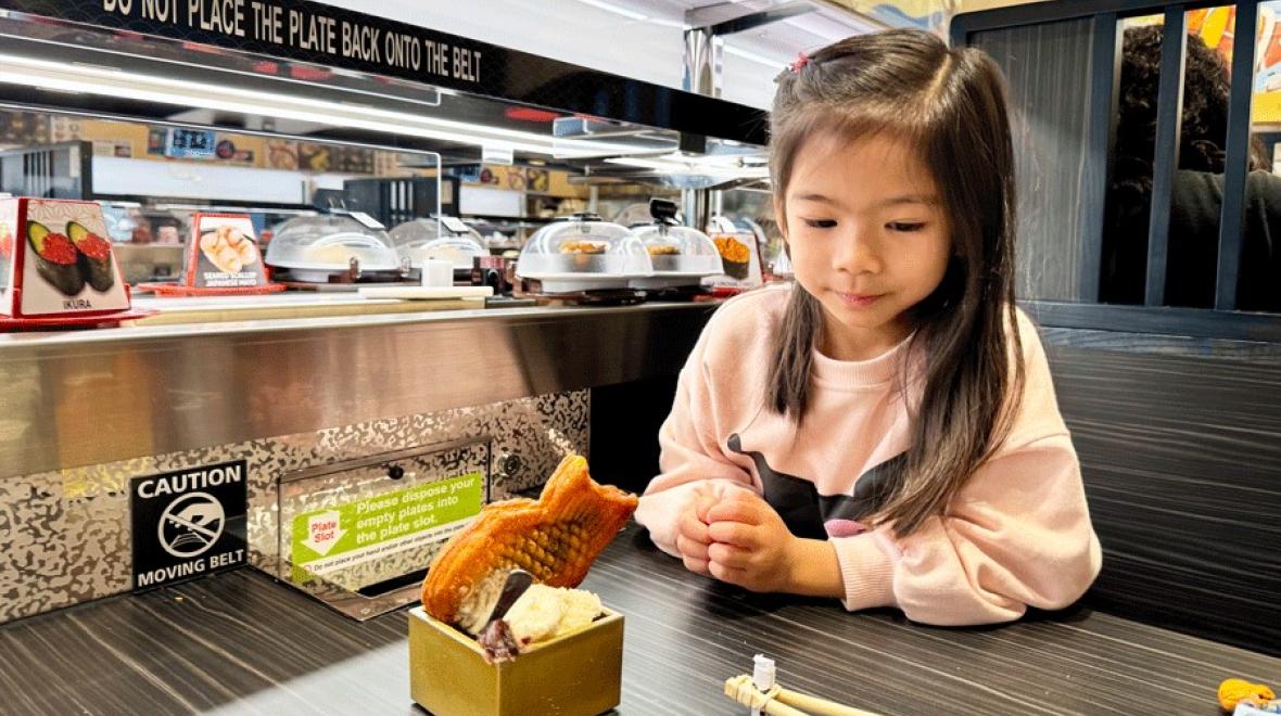 Young girl with ice cream dessert at Kura Sushi, a family-friendly Seattle-area restaurant that makes for a fun fall activity