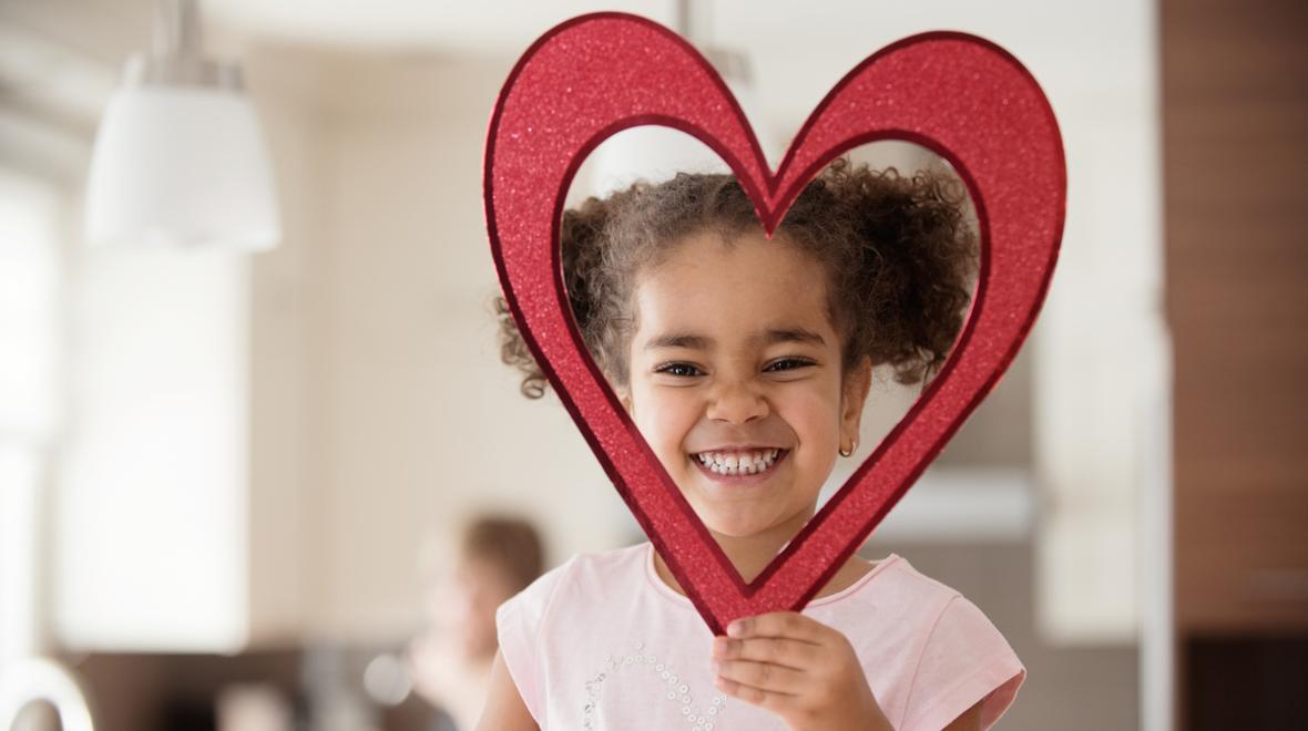 Little girl holding a heart shape around her head